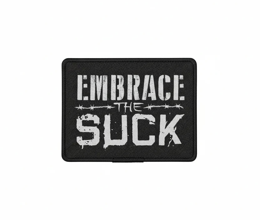 Black patch with white text 'EMBRACE THE SUCK' on a white background